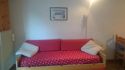 帕索圣佩莱格里诺Rododendro Apartment的配有两个枕头的房间的红色沙发