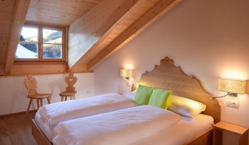 圣坎迪朵Residence Simml & Schlosser的一间卧室配有带白色床单和绿色枕头的床。