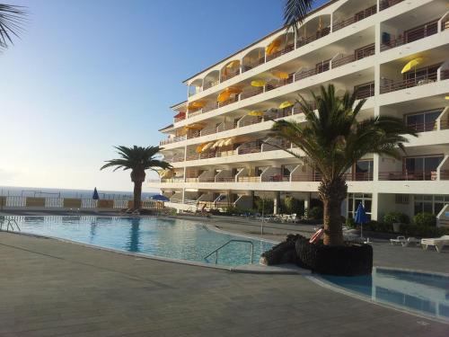 圣地亚哥港La Arena Beach的一座大型公寓楼,设有游泳池和棕榈树