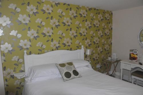 多切斯特悉尼阿姆斯酒店的卧室配有白色的床铺,墙上挂着鲜花