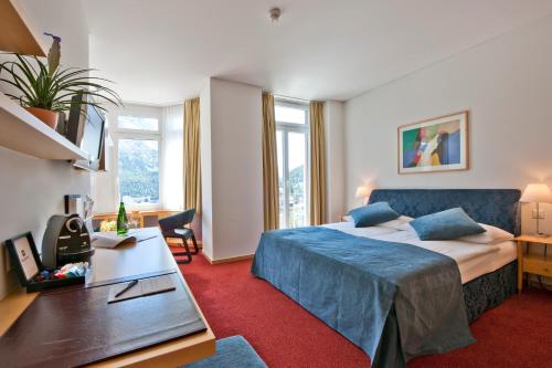 圣莫里茨Hotel Schweizerhof St. Moritz的配有一张床和一张书桌的酒店客房