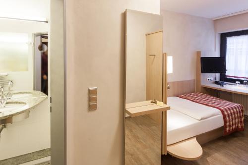 沃尔夫斯堡戈雅中心酒店的小房间设有一张床和一间浴室