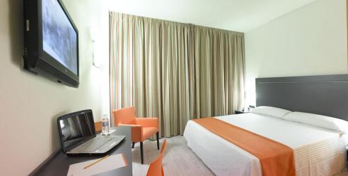 阿维拉H2阿维拉酒店的酒店客房配有一张床铺和一张书桌上的笔记本电脑