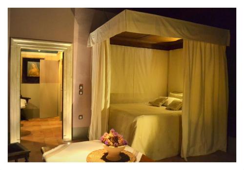 乌尔比诺圣波罗1544仿古客房住宿加早餐旅馆的一间卧室配有天蓬床和鲜花桌