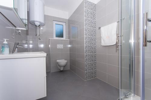 特罗吉尔Apartmani Gaube的带淋浴、盥洗盆和卫生间的浴室