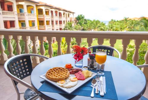 西湾Infinity Bay Spa & Beach Resort的一张带早餐食品和一杯橙汁的桌子
