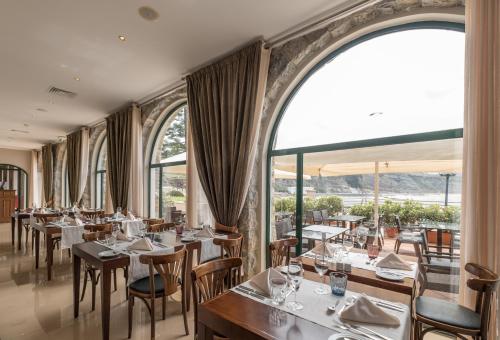 埃里塞拉埃里塞拉嘉乐酒店的餐厅设有桌椅和大窗户。
