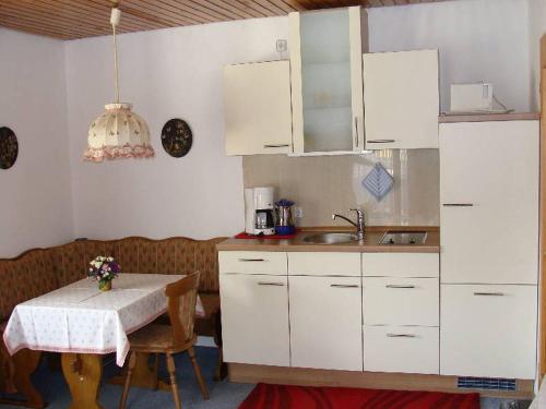 欣特察尔滕Ferienhaus im Grund的厨房配有白色橱柜、桌子和水槽。