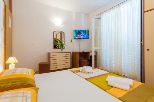 波梅纳Apartments Slavica的一间卧室配有两张床、一个梳妆台和电视。