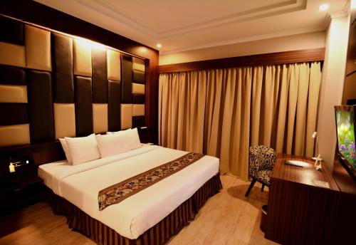 北干巴鲁安卡萨花园酒店的一间卧室配有一张大床、一张桌子和一张书桌