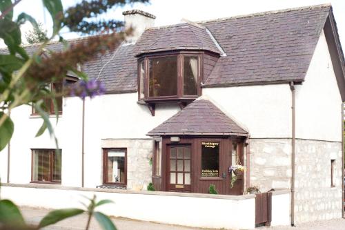 卡布里奇Strathspey Cottage的白色的房子,设有棕色的屋顶和窗户