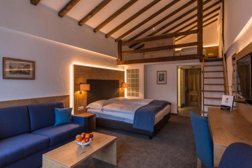 采尔马特Alpen Resort & Spa的一间卧室配有一张床、一张沙发和一张桌子