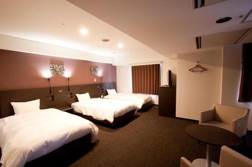 京都京都四条微笑酒店的酒店客房,配有两张床和椅子