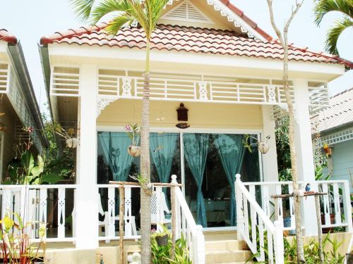 华欣普拉塔纳花园海滩度假酒店的前面有棕榈树的房子