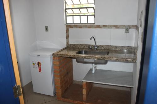 蒂拉登特斯Pousada Serra Azul的厨房配有水槽和小冰箱