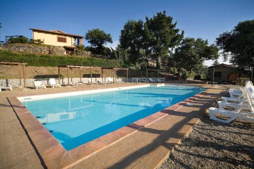 蒙蒂菲阿斯科尼AgriResort Spa Glamping Poggio Di Montedoro的一个带椅子的游泳池和一个背景房子