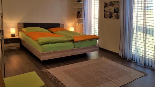 OberlienzFerienwohnung Dolomitenpanorama的一间卧室配有带绿床单和橙色枕头的床