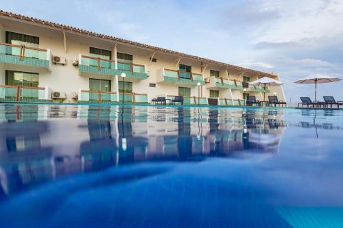 巴纳伊巴Arrey Hotel Beach的酒店游泳池设有椅子和遮阳伞