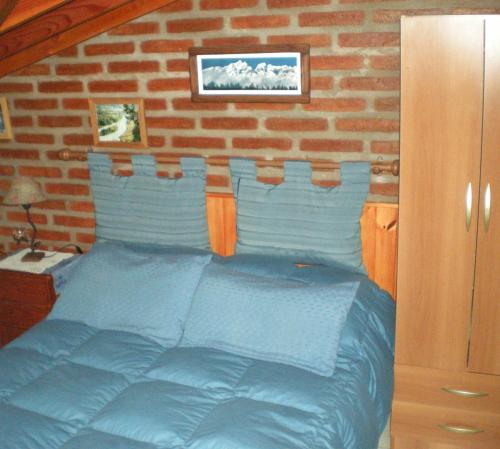 埃博森卡瓦尼亚斯图仁旅馆的一间卧室配有一张蓝色的床和砖墙