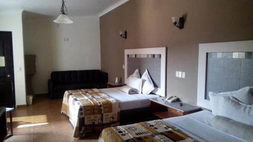 瓜达拉哈拉阿卡勒斯汽车旅馆的酒店客房,设有两张床和一张沙发