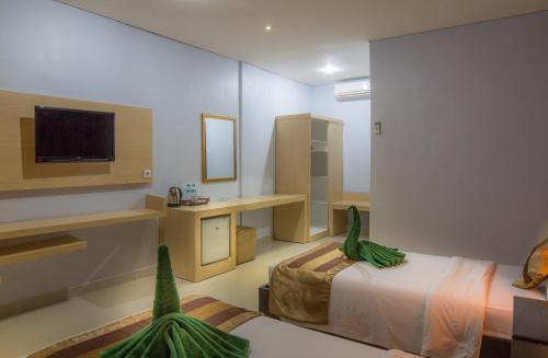 库塔水仙花海滩度假酒店的客房设有带一张床和电视的卧室。