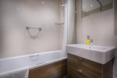 霍姆弗斯The Old Bridge Inn, Holmfirth, West Yorkshire的浴室配有盥洗盆、浴缸、盥洗盆和镜子