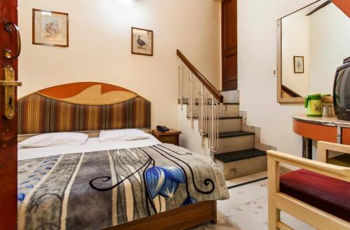 新德里阳光大酒店 的一间卧室设有一张床和一个楼梯