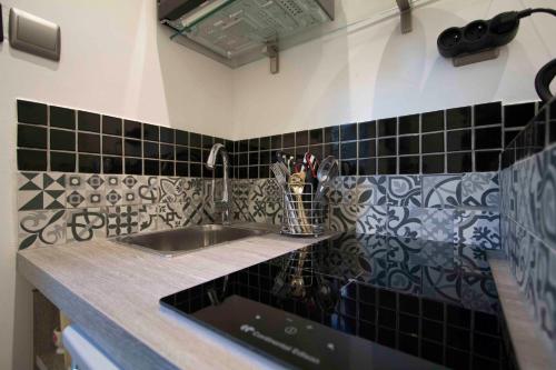 巴黎巴黎圣母院拉丁天堂公寓的厨房柜台设有水槽和黑色瓷砖