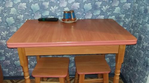 KhrystynivkaHotel Yuvileyny的一张木桌,配有两个凳子和粉红色的顶部