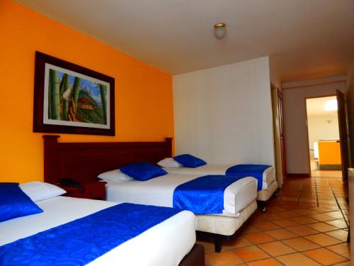亚美尼亚卡斯蒂略里尔酒店的橙色墙壁的酒店客房内的两张床