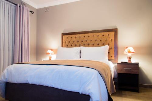 哈拉雷撒瑞姆小屋酒店的一间卧室配有一张大床和木制床头板