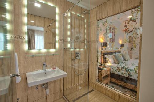 萨拉热窝阿兹扎酒店的一间带水槽和镜子的浴室以及一张床