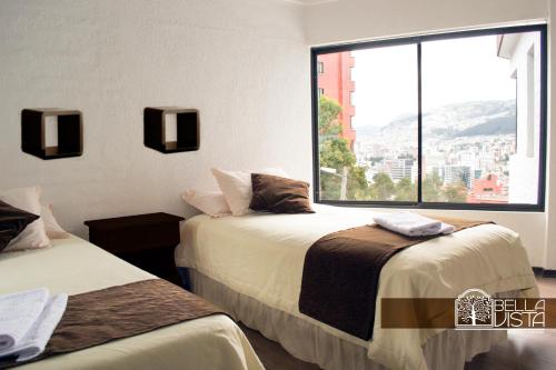 基多Hotel Bellavista Quito的带大窗户的客房内的两张床