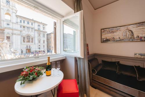 罗马纳沃纳雷亚西尔维娅豪华旅馆的一张桌子,上面放着一瓶葡萄酒,还有一个窗口