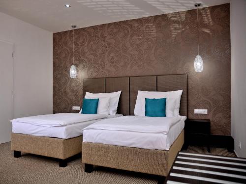 帕尔杜比采中庭酒店的两张位于酒店客房的床,配有蓝色枕头