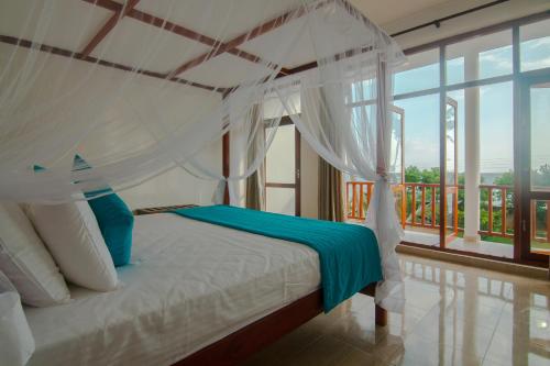 马特勒Savenrose Beach Villa的一间卧室设有一张天蓬床和一个阳台