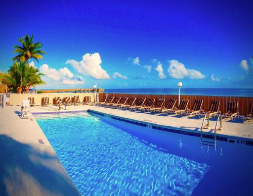 马拉松克殖民地海滩汽车旅馆的一个带椅子的游泳池,背景是大海