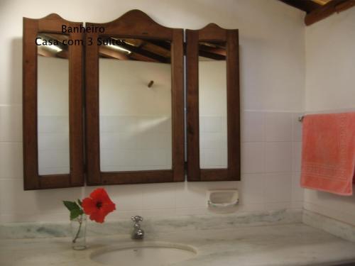 托兰克索Condominio dos Nativos的浴室水槽设有镜子和红花