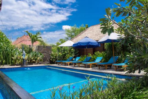 蓝梦岛Koji Garden Huts - CHSE Certified的度假村的游泳池,配有蓝色的椅子和遮阳伞
