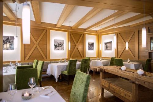 泰塞罗Hotel Al Cervo的用餐室配有桌子和绿色椅子