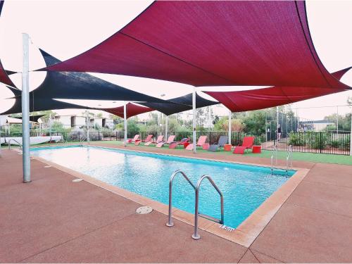 纽曼摩羯村酒店的游泳池上设有红色和黑色的遮阳伞