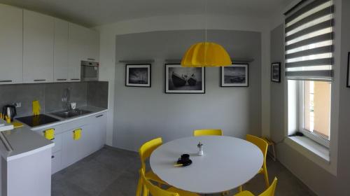 格但斯克Bajkowa Plaża - Muszelka的厨房配有白色的桌子和黄色的椅子