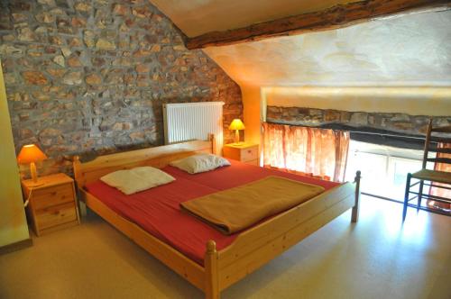 FasolFermette Erpigny的一间卧室设有一张木床和石墙