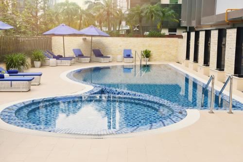 河内河内诺富特套房酒店的一座大楼内的游泳池,配有椅子和遮阳伞