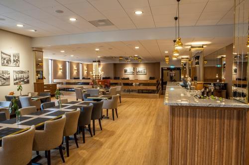 奈舍何格兰酒店的一间带桌椅的餐厅和一间酒吧