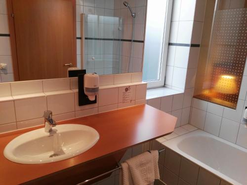 施泰尔兰德格斯托弗维特菲尔德酒店的浴室配有盥洗盆、镜子和浴缸