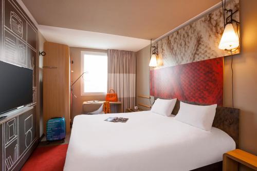 翁弗勒尔翁弗勒尔宜必思酒店的酒店客房设有一张白色大床和电视。