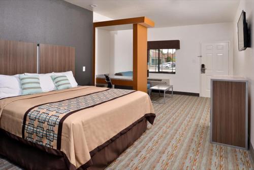 孔洛Scottish Inn & Suites - Conroe的酒店客房设有一张大床和一台电视。