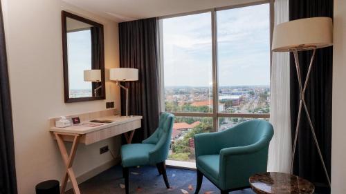 三宝垄潘达纳兰路易斯肯尼酒店的客房设有书桌、两把椅子和窗户。