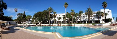 哈马马特贝拉祖尔特拉所简易别墅酒店的棕榈树建筑前的游泳池